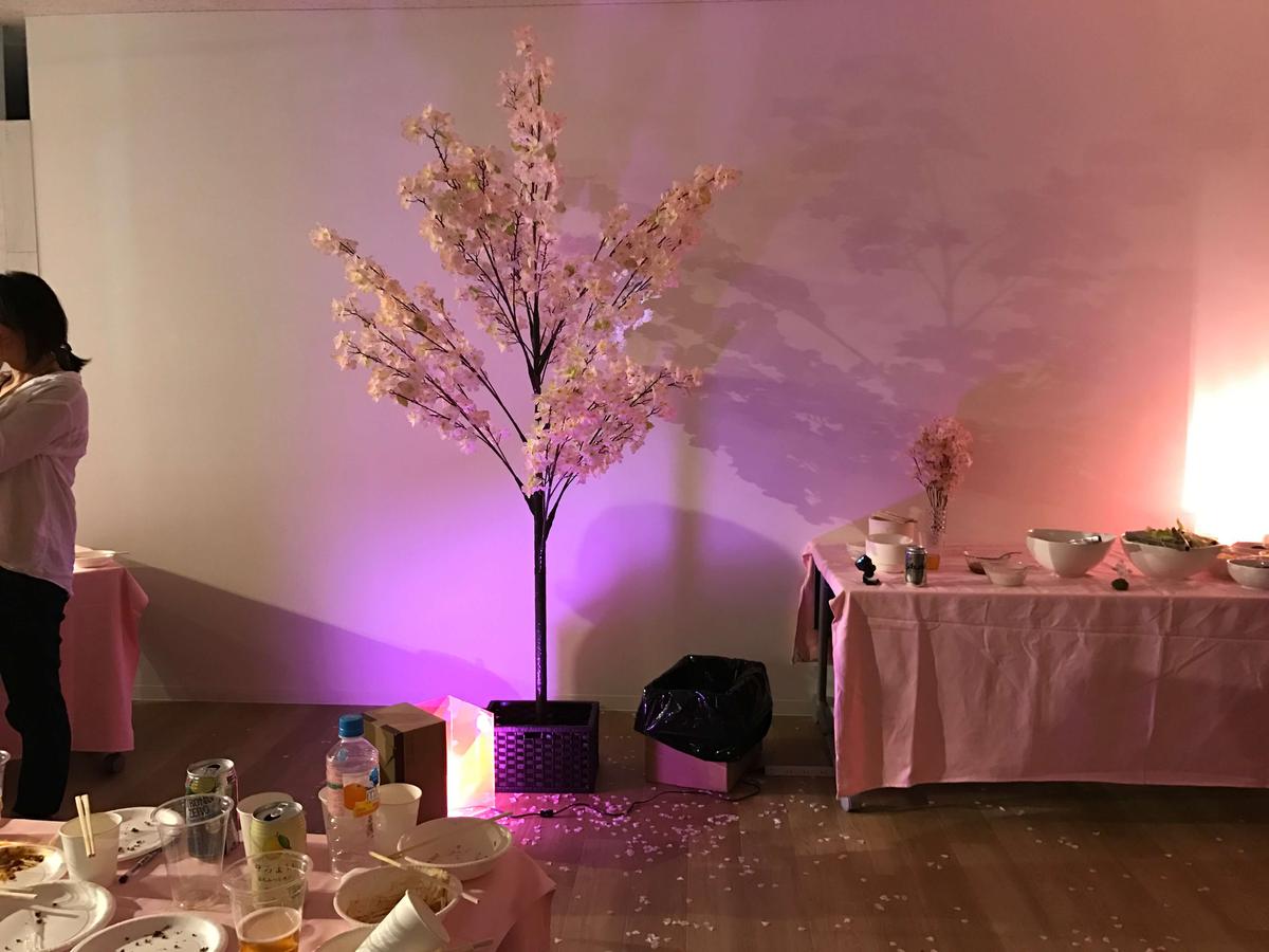 桜の木の造花と、それを照らす照明、周りに散らばる作り物の桜の花びら
